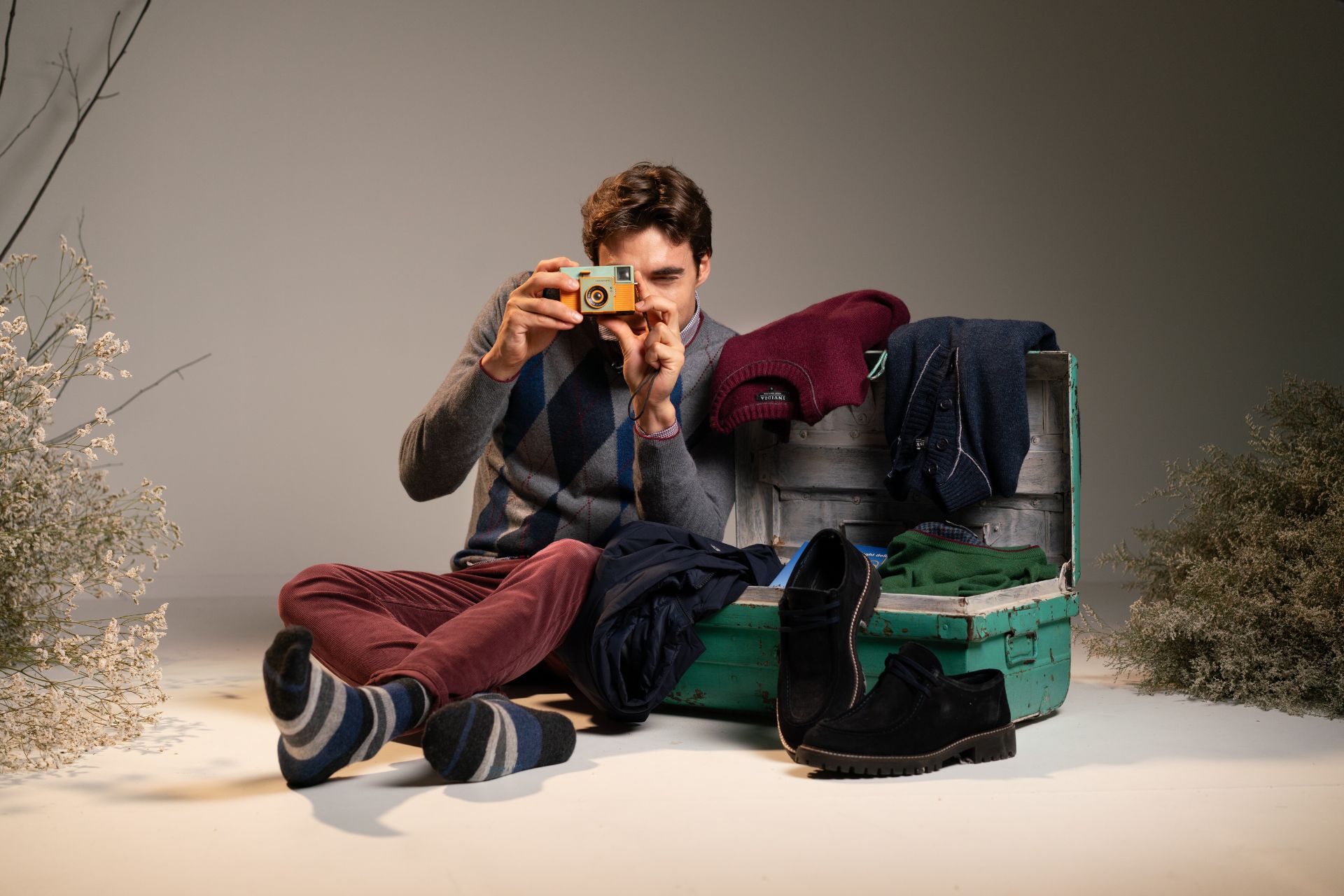 Ragazzo che scatta una foto e valigia aperta con maglieria uomo