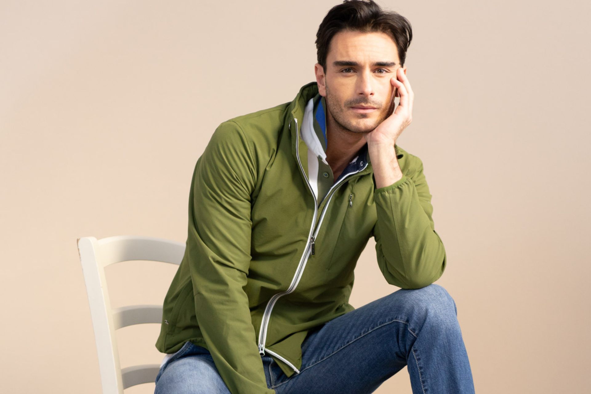 ragazzo seduto indossa jeans e giacca antivento